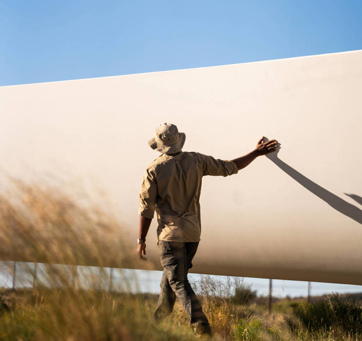 Wind farm worker touching base of a wind turbine. 