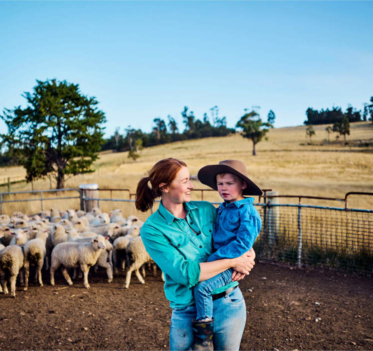 A mother and son in a paddock with a herd of sheep
